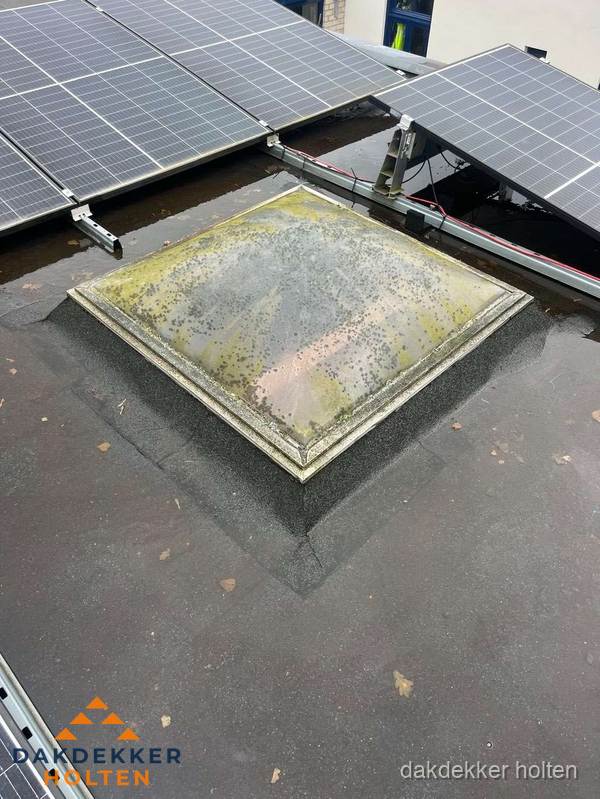Vervuilde lichtkoepel op plat dak met zonnepanelen in Holten