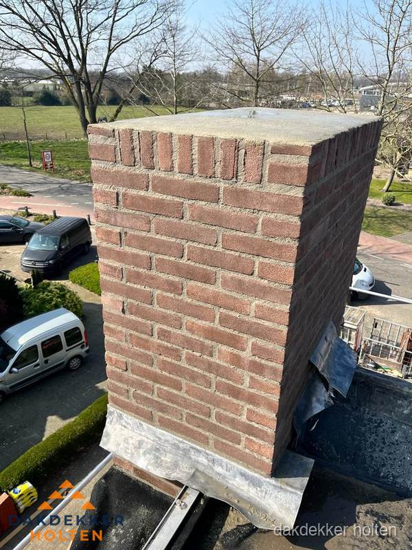 Gemetselde schoorsteen met loodaansluiting op dak in Holten