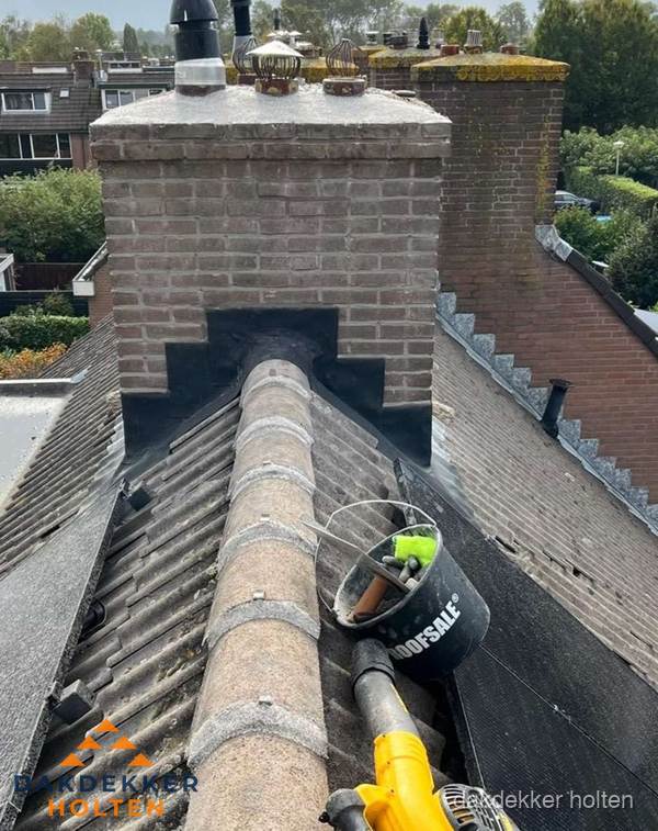 Schoorsteen met loodaansluiting en nokvorst op pannendak in Holten