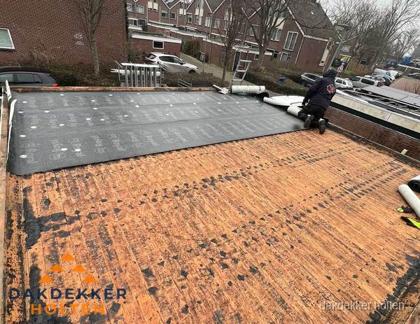 Dakdekker legt onderlaag op plat dak met houten constructie in Holten
