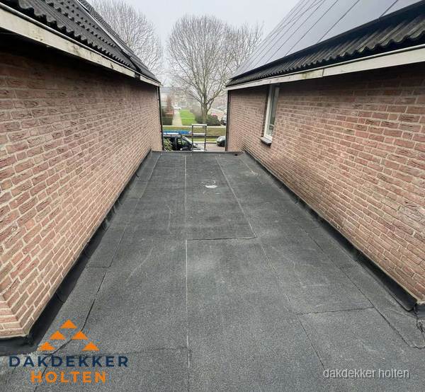 Plat dak met bitumen dakbedekking tussen bakstenen muren in Holten