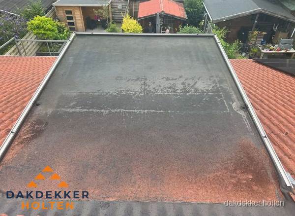 Verouderd plat dak met slijtage tussen schuine daken in Holten