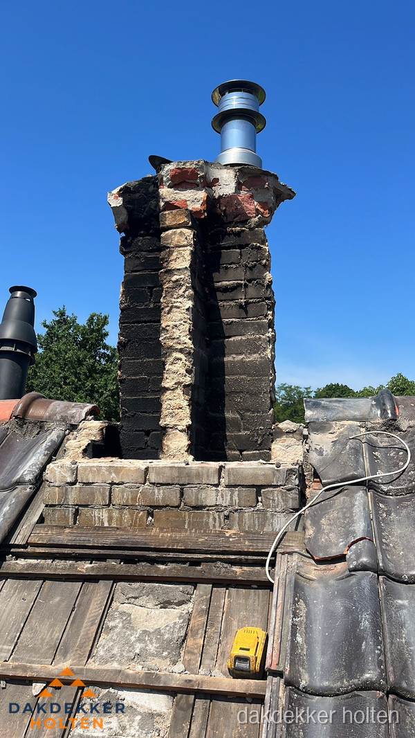 Beschadigde schoorsteen met nieuwe rookgasafvoer op oud dak in Holten