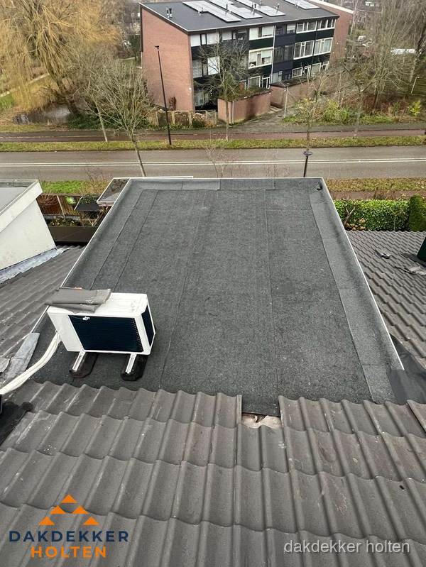 Plat dak inspectie met bitumen bedekking naast schuin pannendak in Holten
